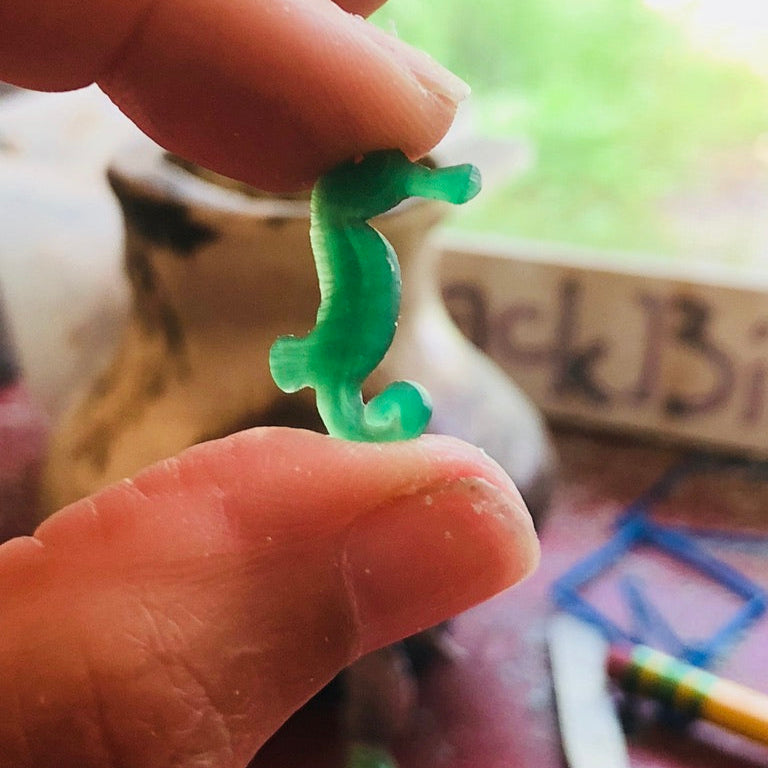 hand holding sea wax carving on workbench