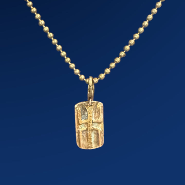 bronze tao wood charm on chain on blue background