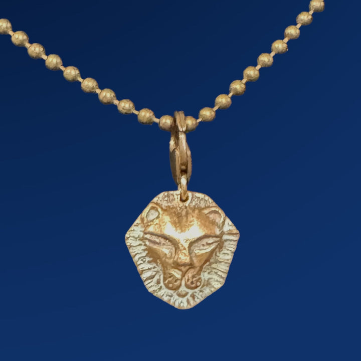 small bronze lion charm on chain on blue backgroun