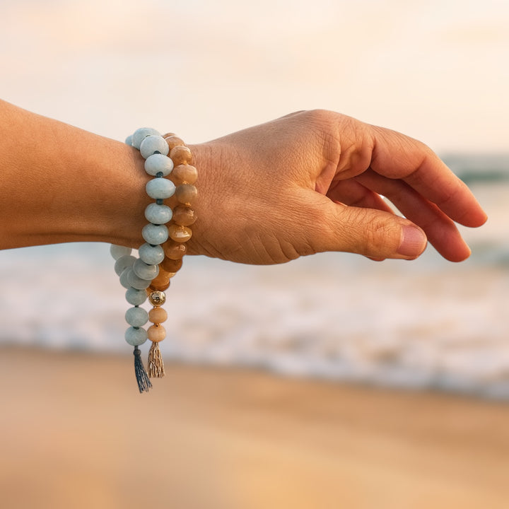 Sunkissed sunstone and salty amazonite gemstone bracelets on wrist by beach