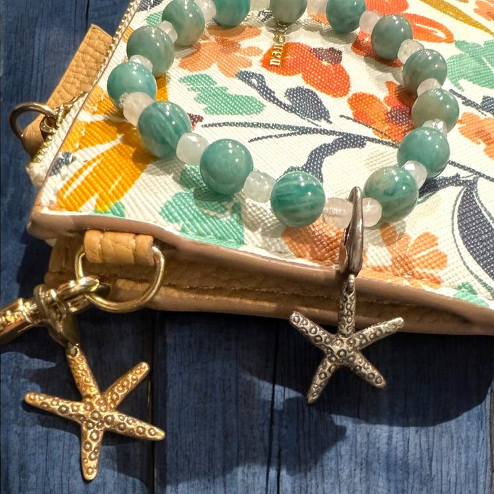 star fish charms on bracelet and purse on blue wood table