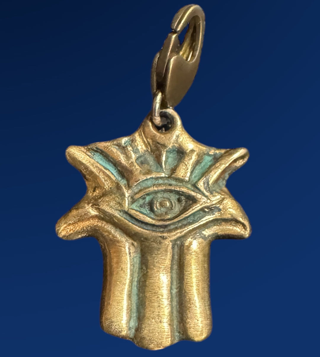 green patina on bronze hamsa charm on blue background