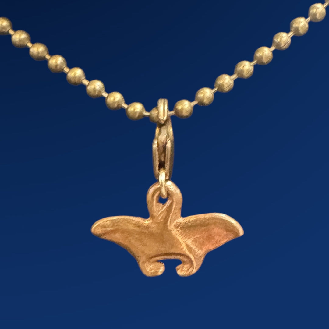 bronze manta ray charm on chain on blue background