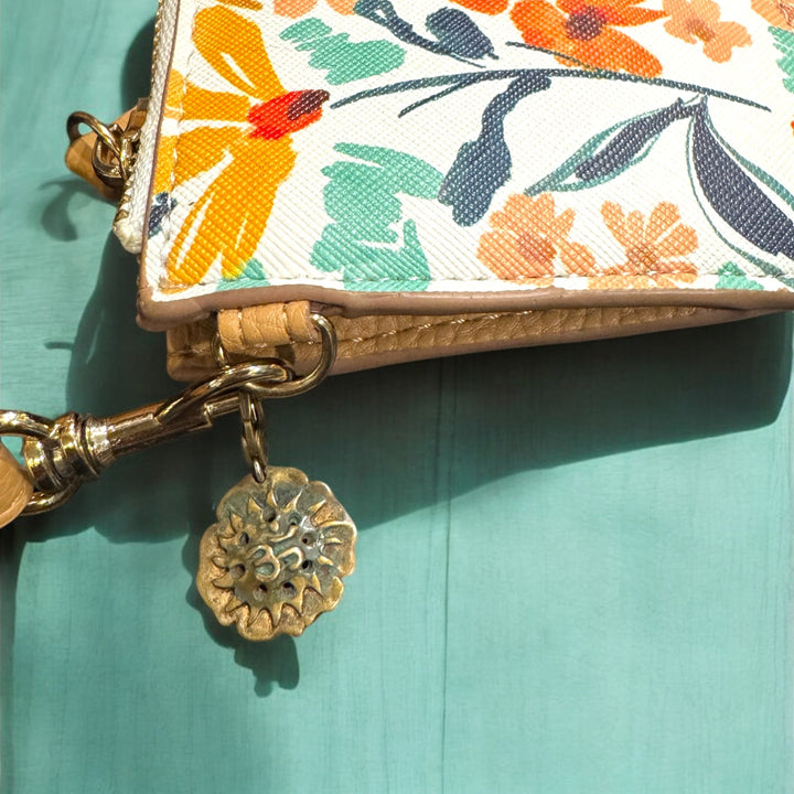Floral-patterned pouch with a gold charm on a teal background