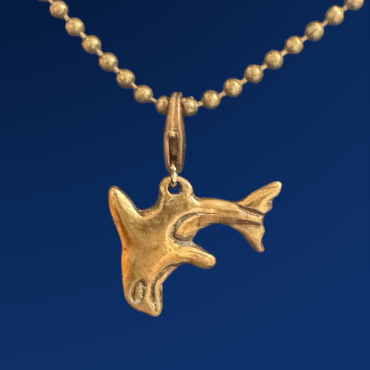 bronze orca charm on chain on blue background