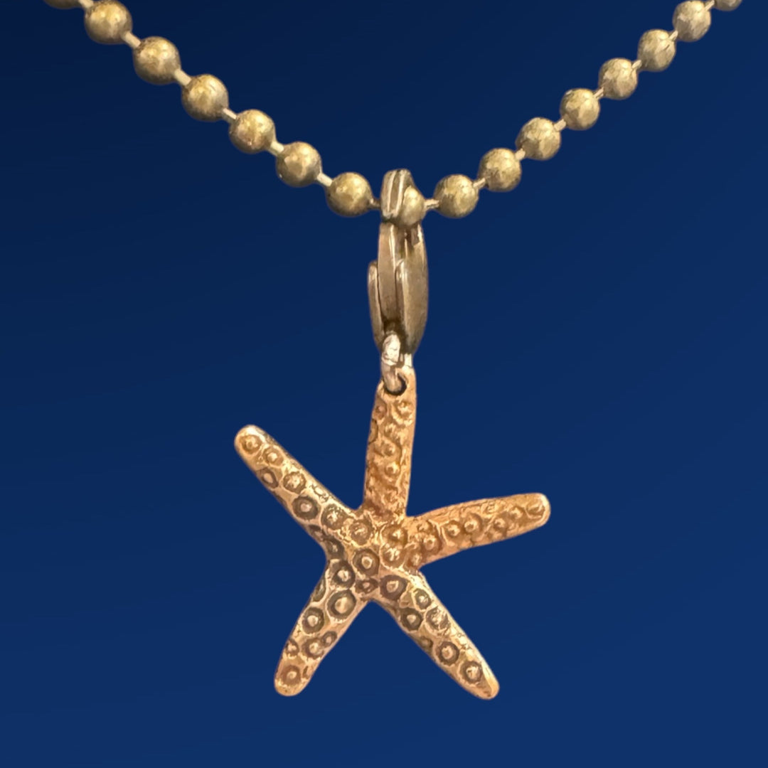 bronze star fish charm  on chain on blue background