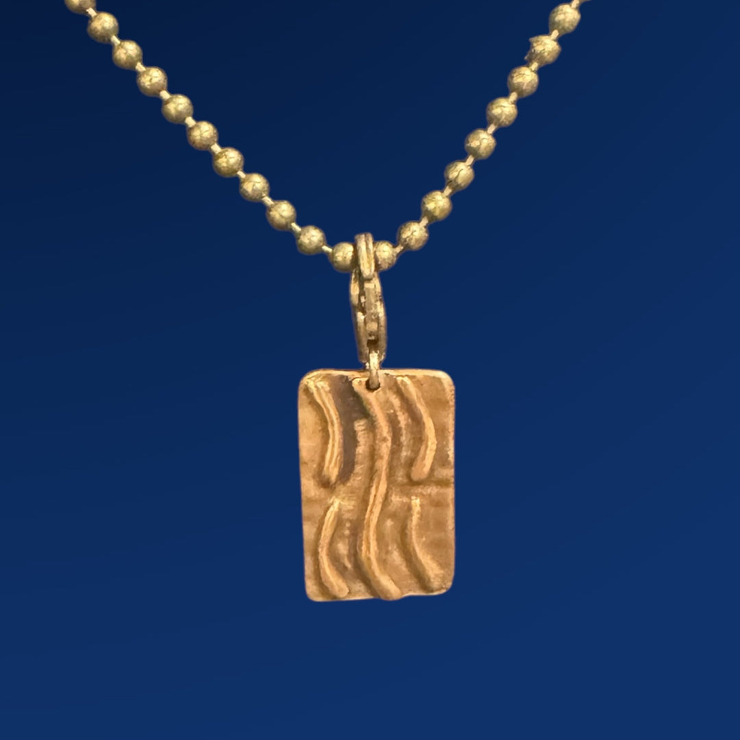 bronze water tao charm on chain and blue background