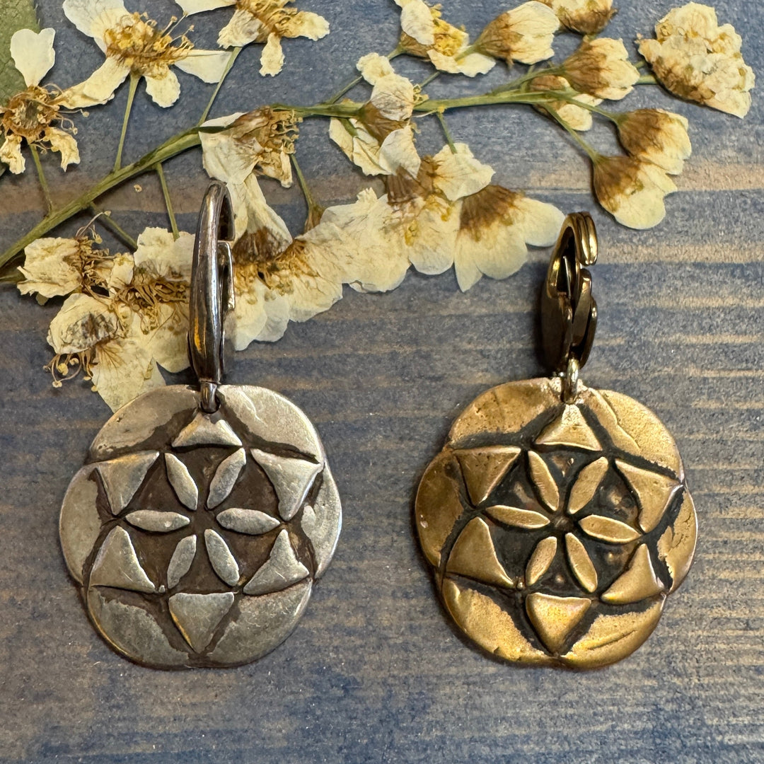 silver and bronze seed of life charms on dried flowers