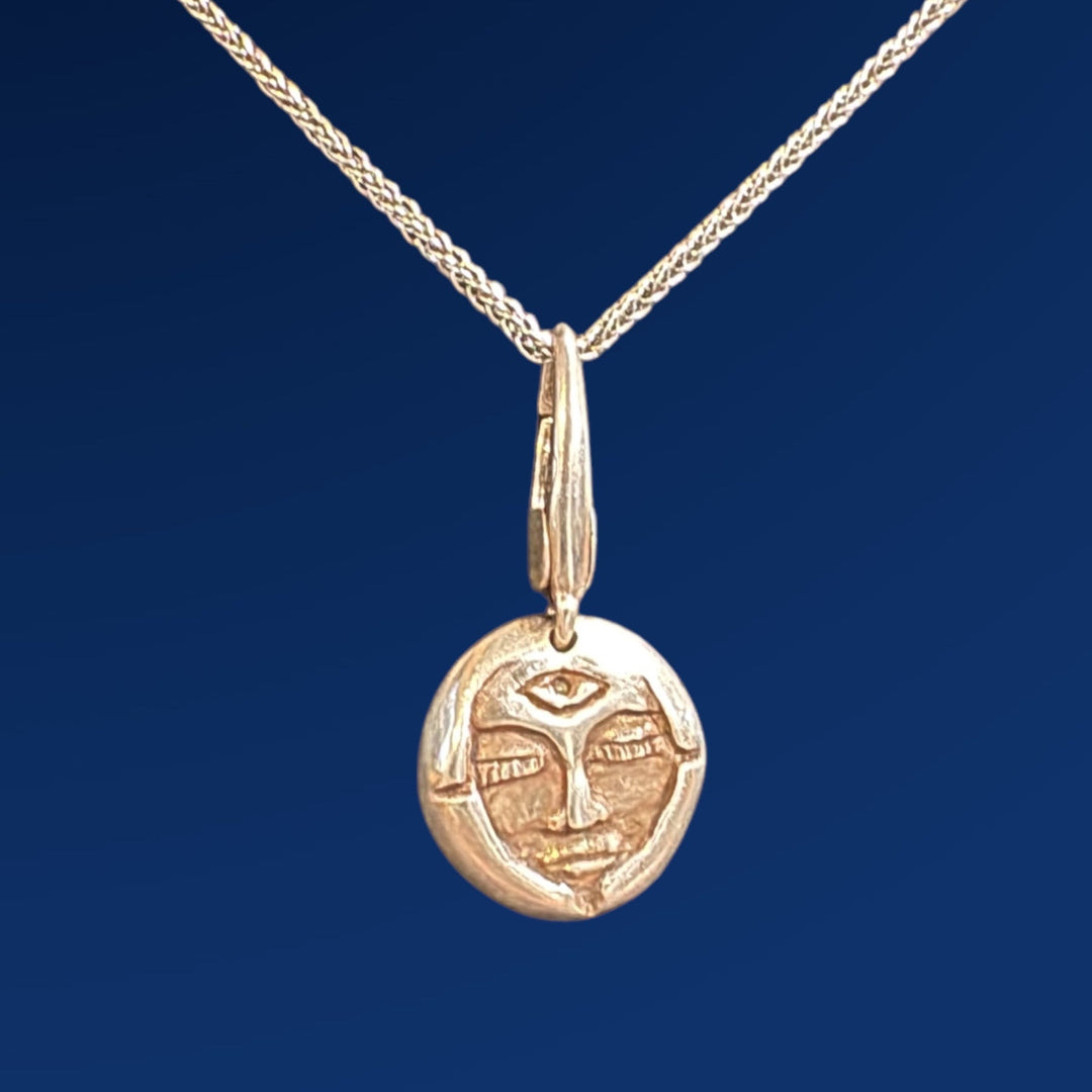 silver emerge charm on chain on blue background