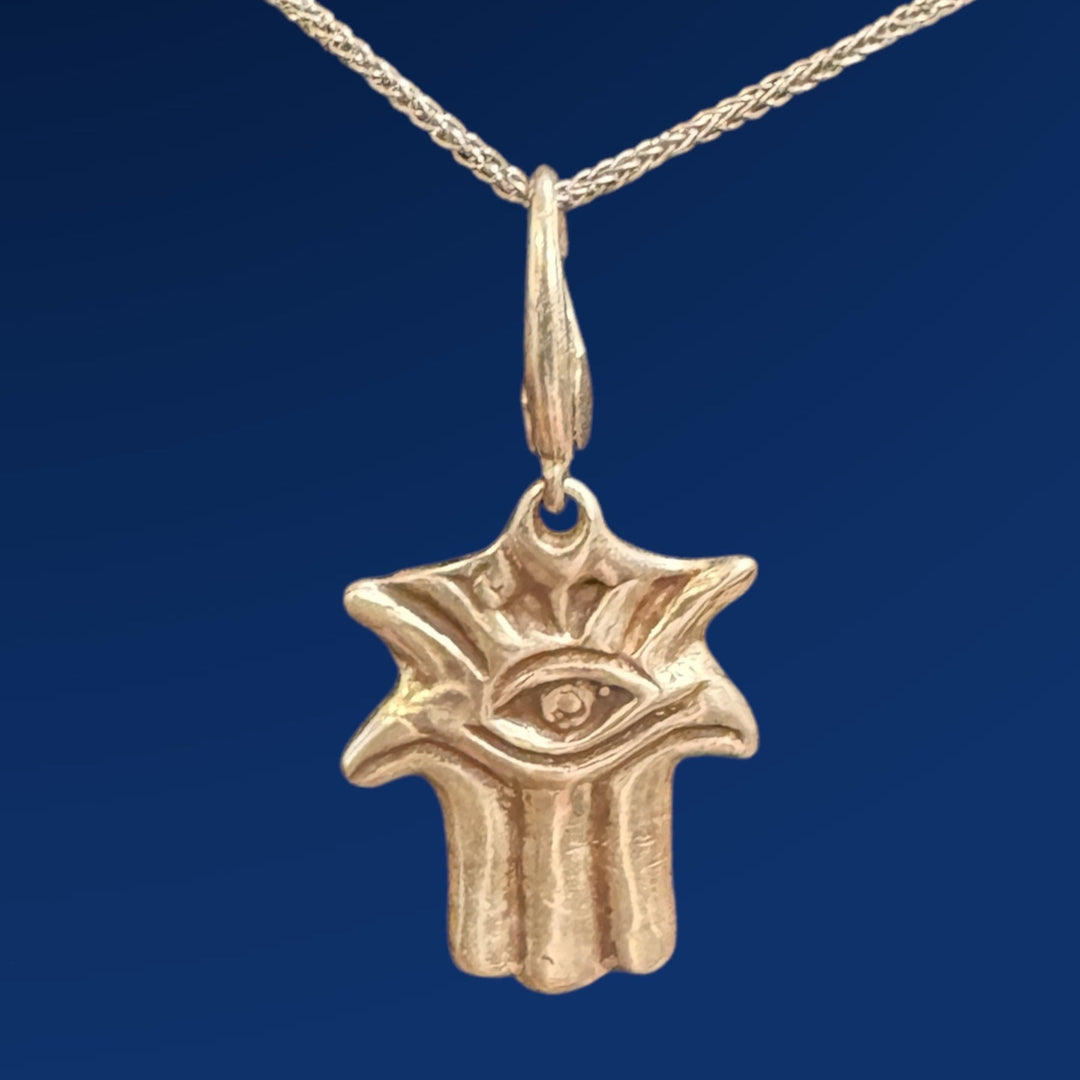 silver hamsa charm on chain with blue background