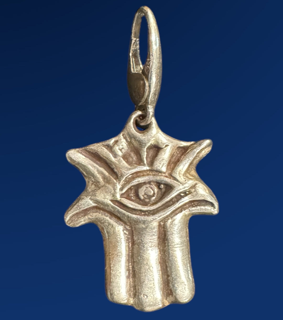silver hamsa charm on blue background