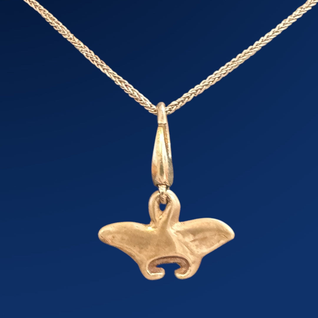 silver manta ray charm on chain on blue background