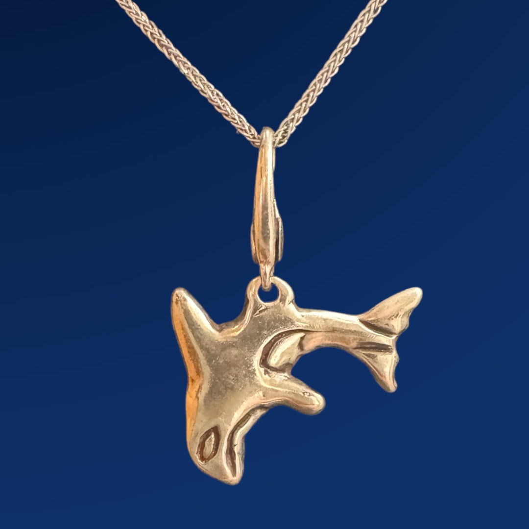 silver orca charm on chain on blue background