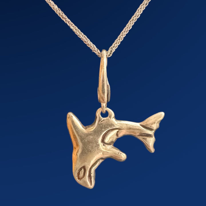 silver orca charm on chain on blue background