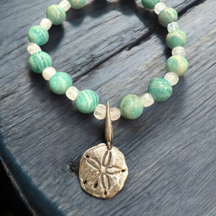 bead blue bracelet with sand dollar charm on blue table