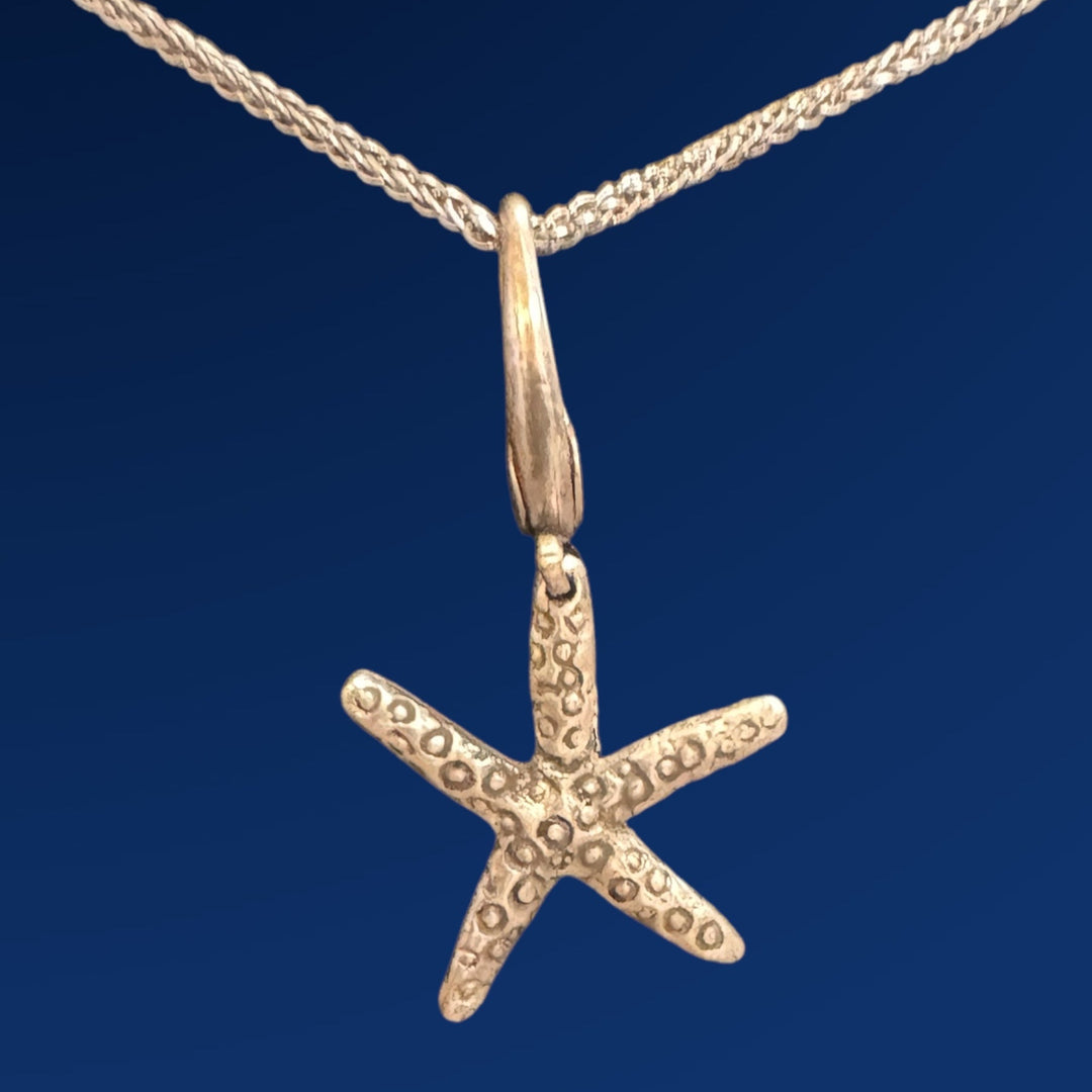 silver starfish charm on chain on blue background