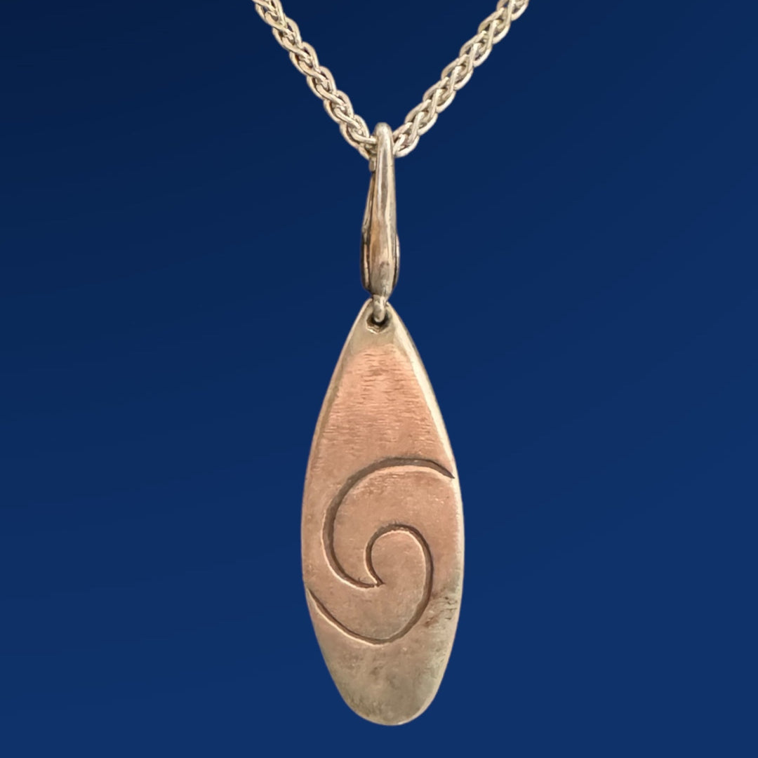 silver surfboard pendant on silver chain on blue background