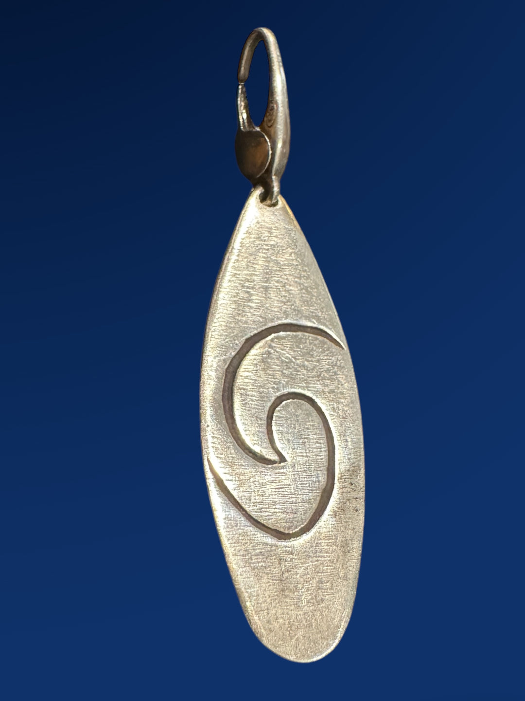 silver surfboard charm with spiral on blue background
