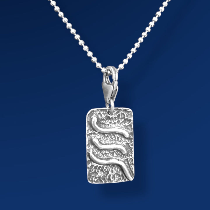 silver tao air charm on chain and blue background