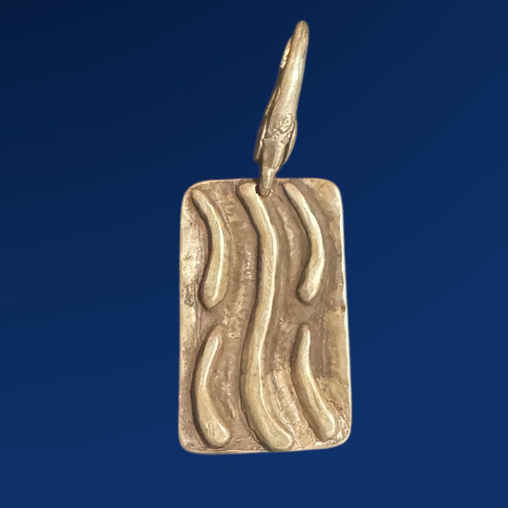 silver tao water charm on blue background