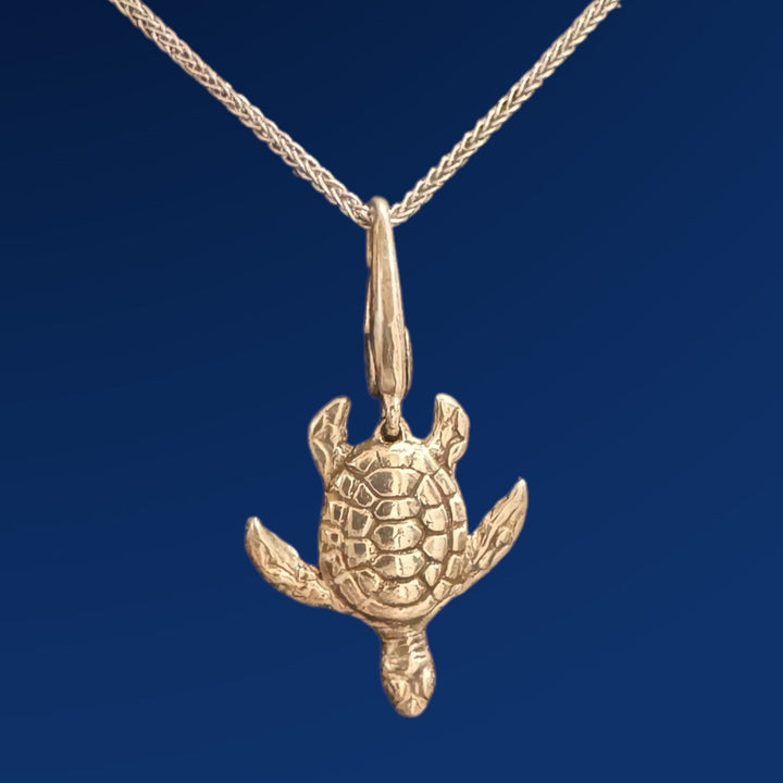 silver sea turtle charm on chain on blue background