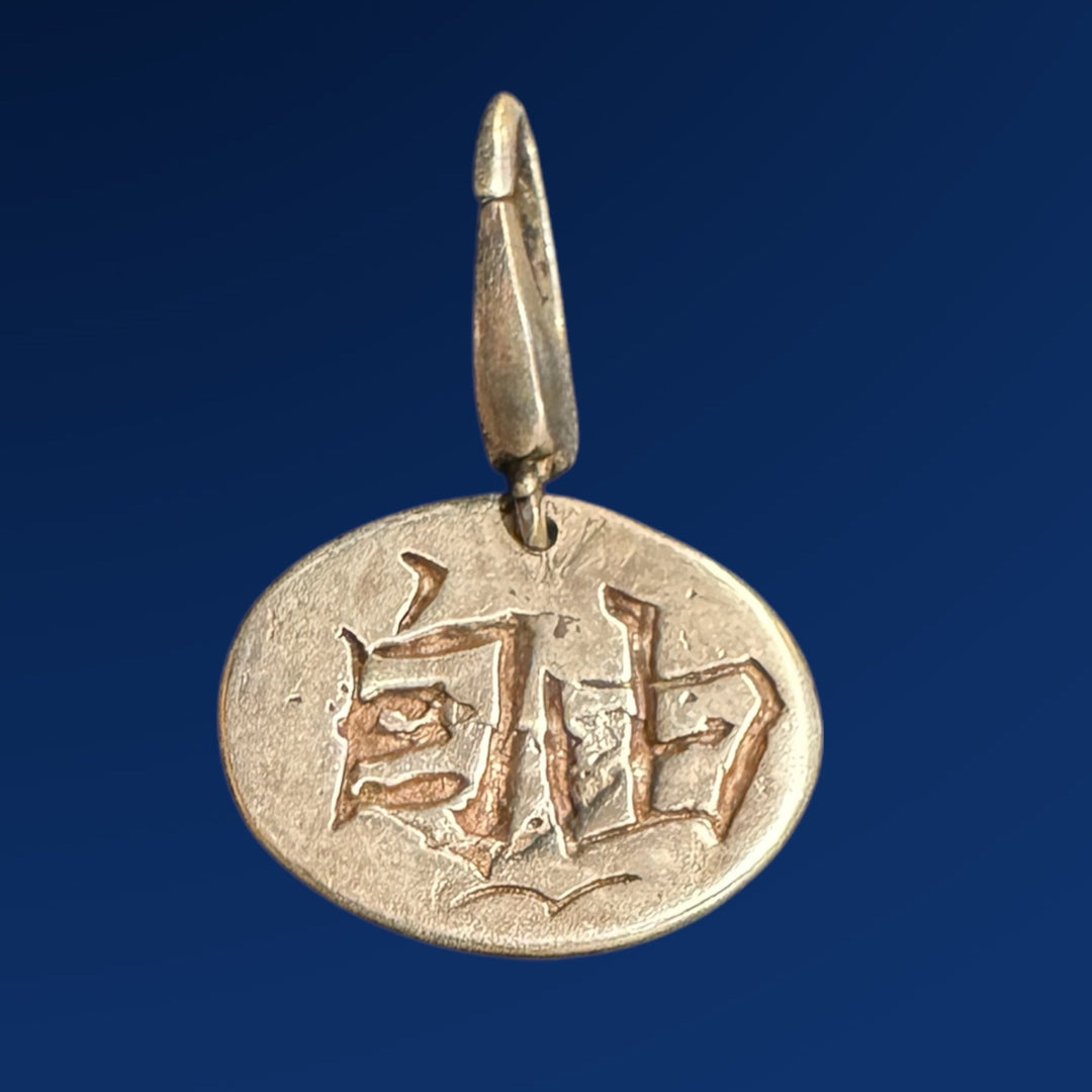 silver charm with Japanese writing on blue background