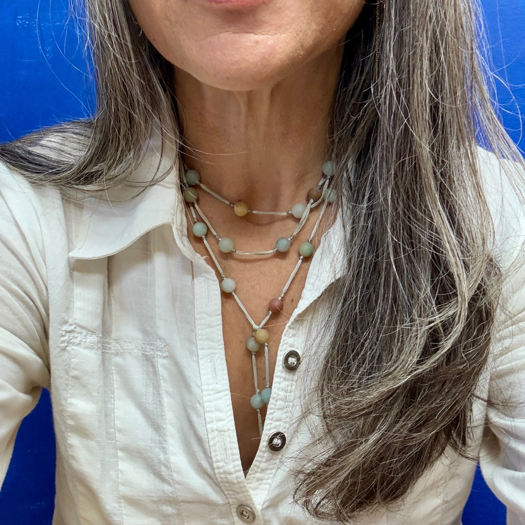 Person wearing layered amazonite meditation necklace with a blue background