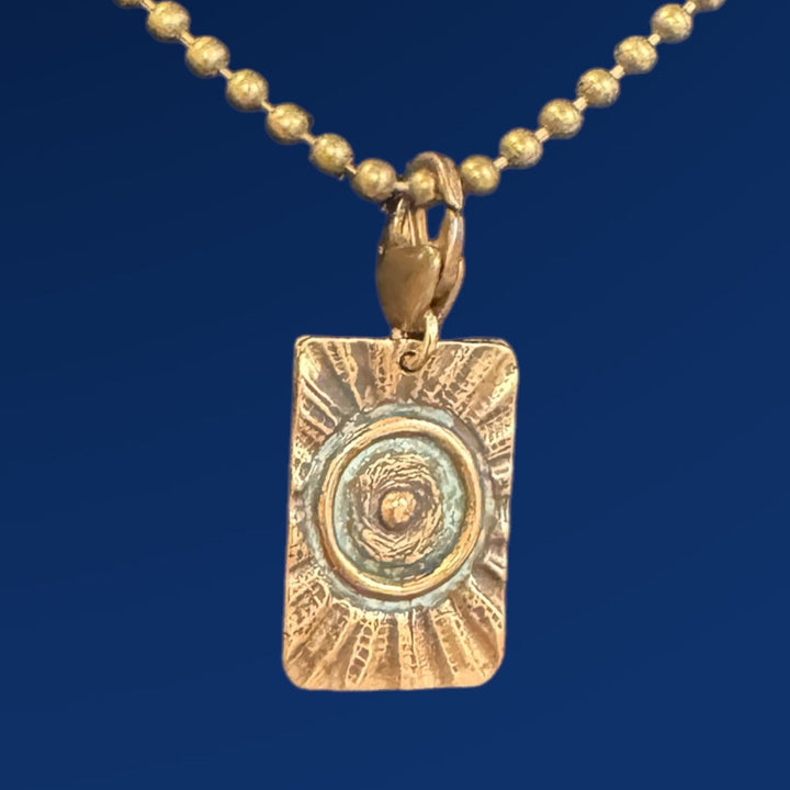 bronze tao fire charm on chain and blue background