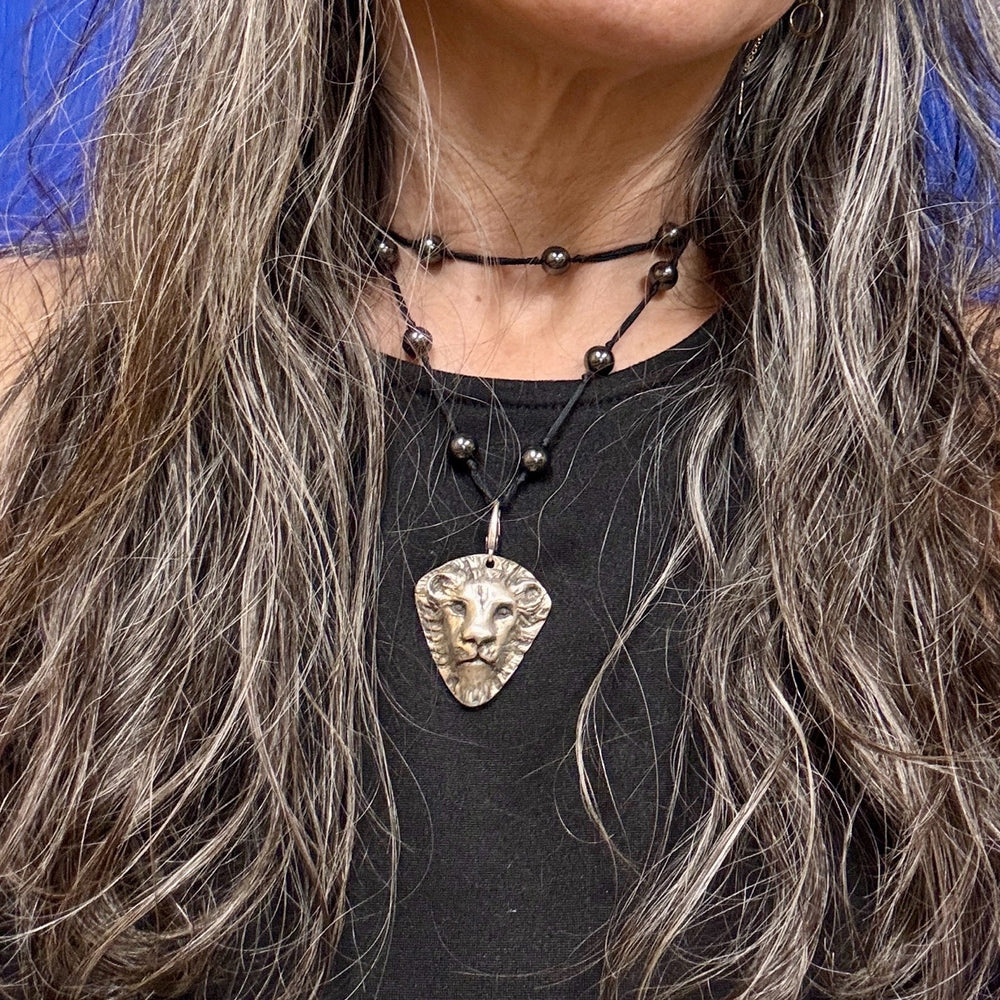 person wearing a lion necklace on beads
