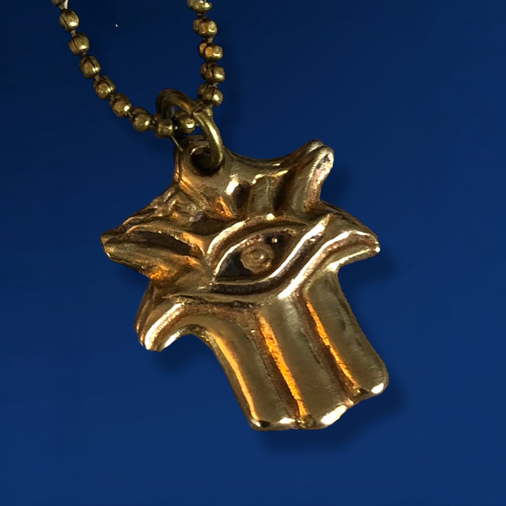 bronze hamsa on ball chain on blue background
