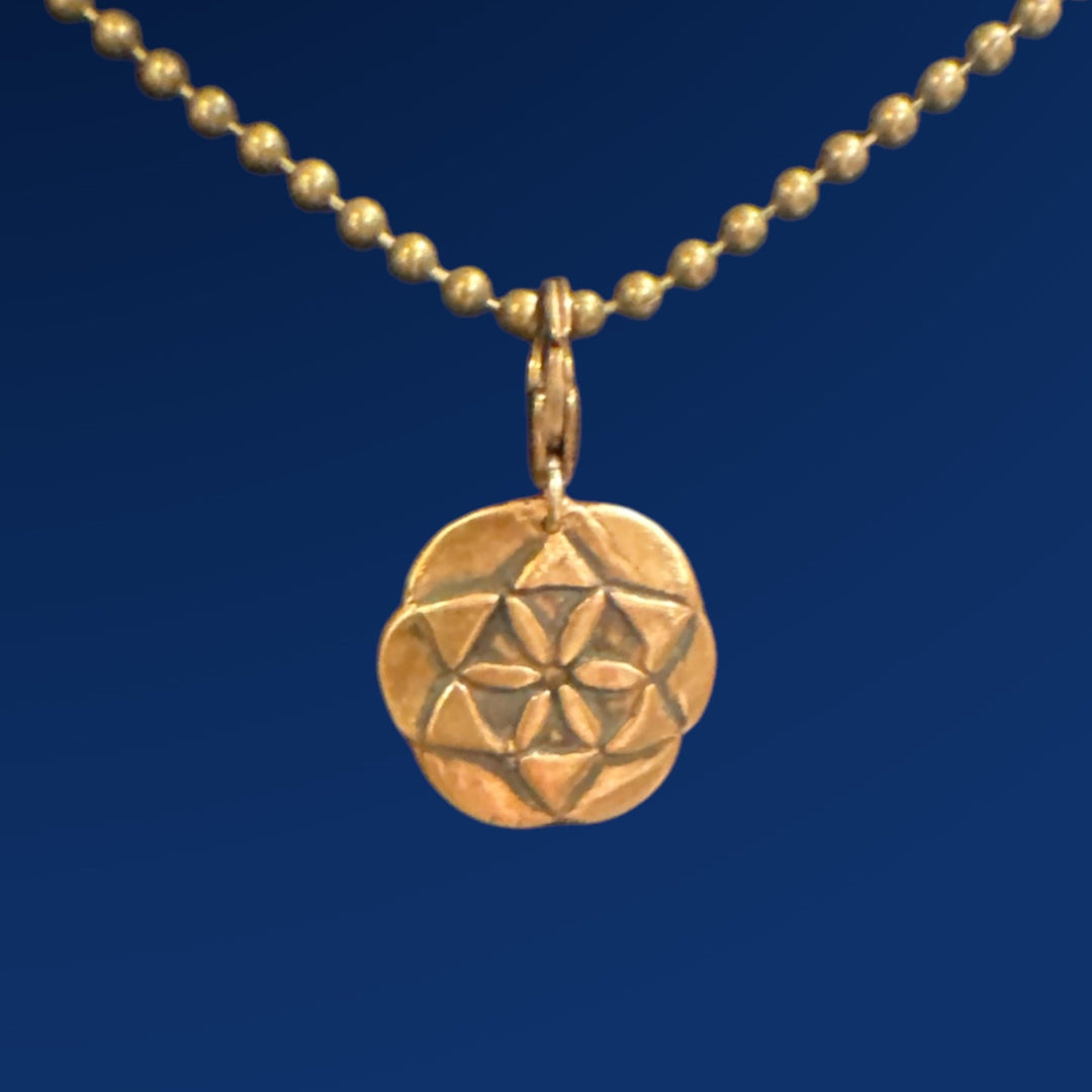 bronze seed of life charm on ball chain on blue background