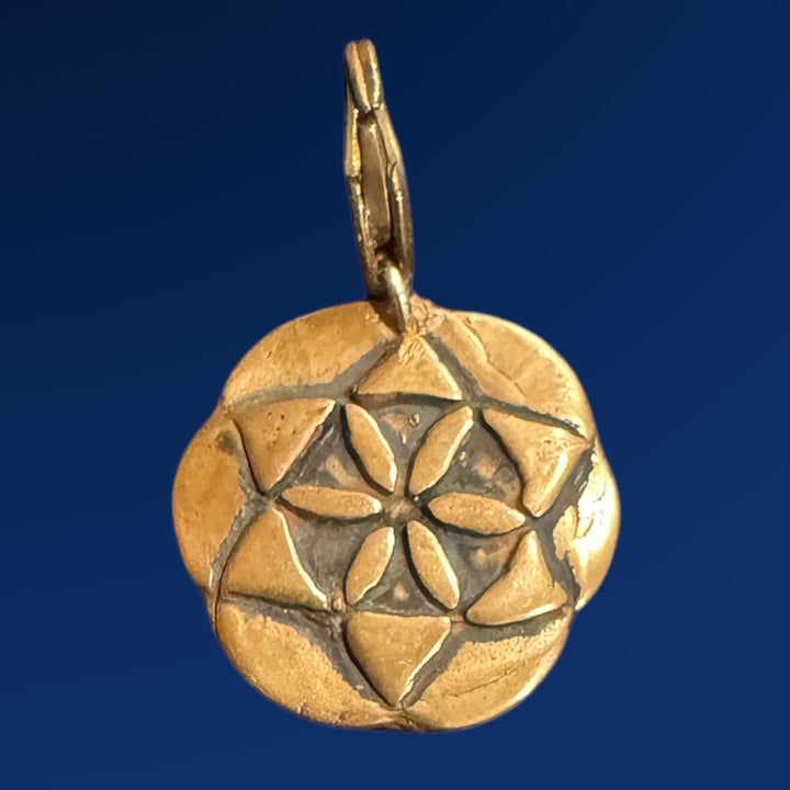 bronze seed of life charm on blue background

