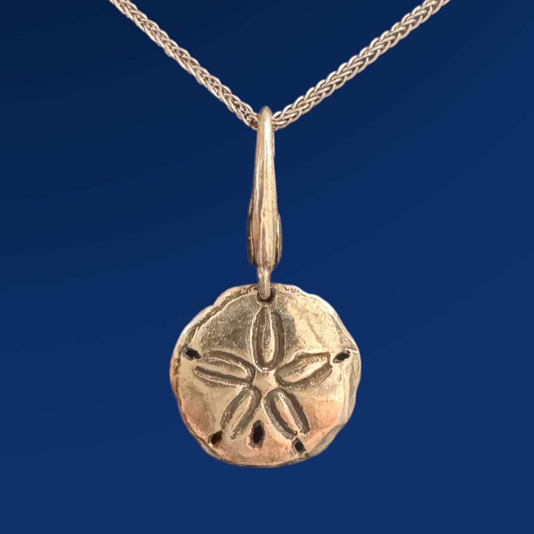 silver sand dollar charm on chain on blue background
